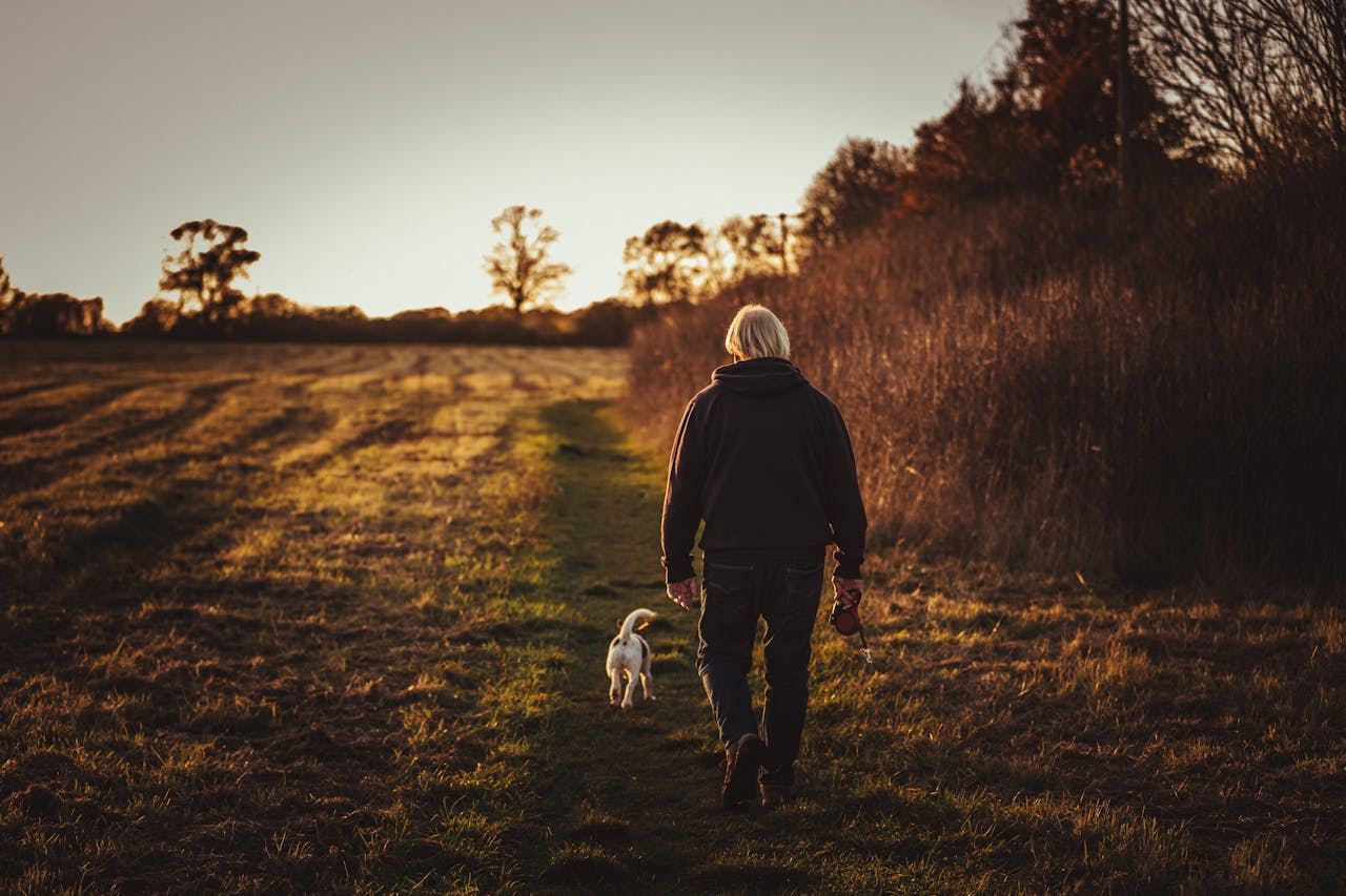 Older man walking on a field with a dog