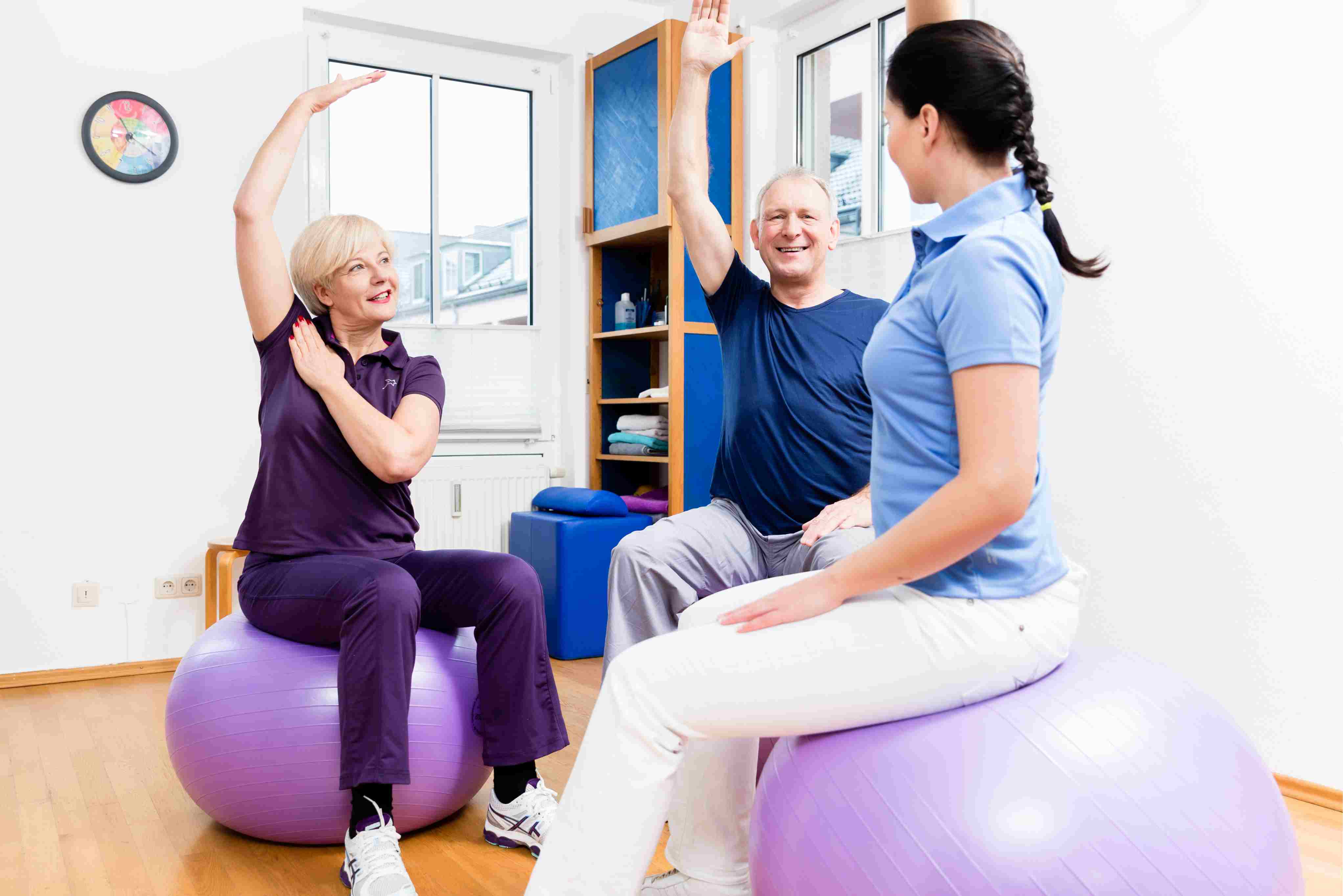 A care professional guides two seniors through strength and balance exercises using fitness balls, promoting mobility, confidence, and physical independence.